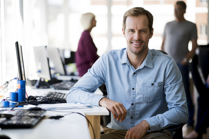 Smiling businessman sitting at computer desk