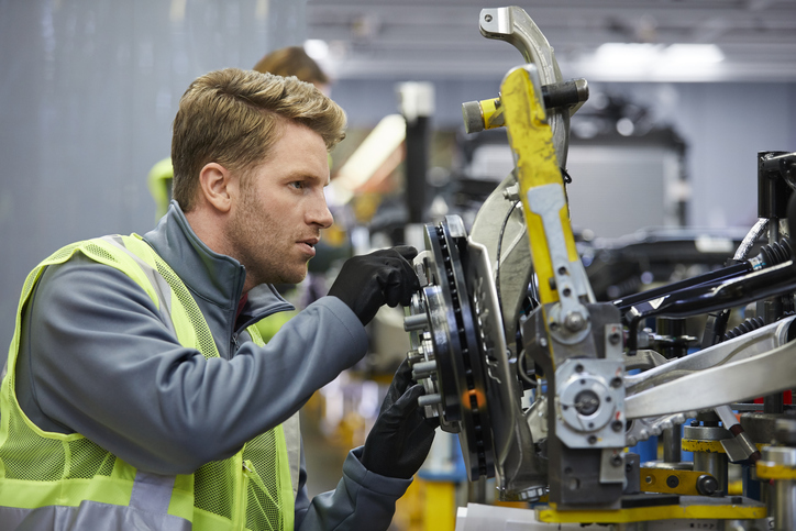 Confident male engineer examining car chassis