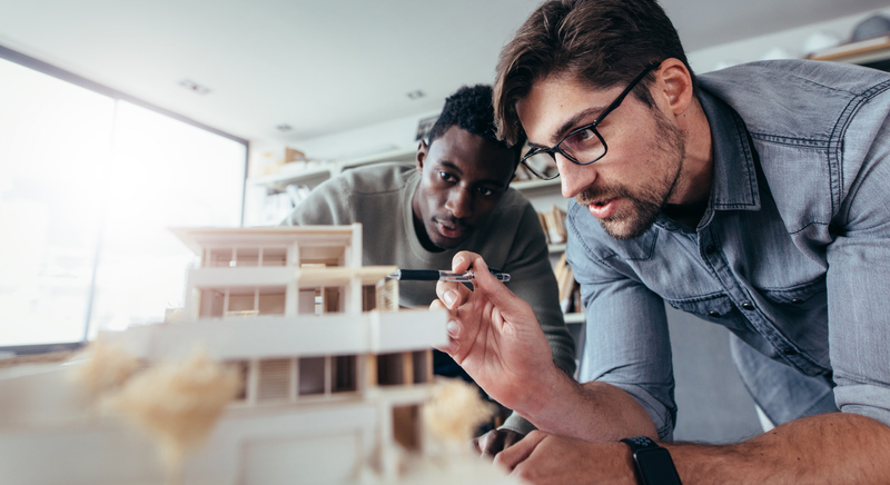 Two male architects discussing over house model