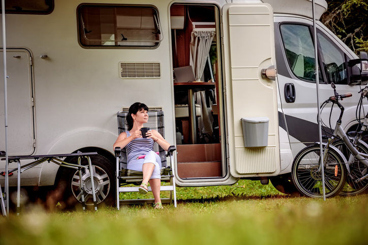 Woman is standing with a mug of coffee near the camper RV.